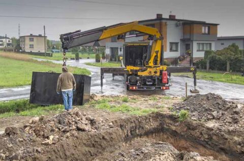 a man standing in dirt next to a large hole in the ground