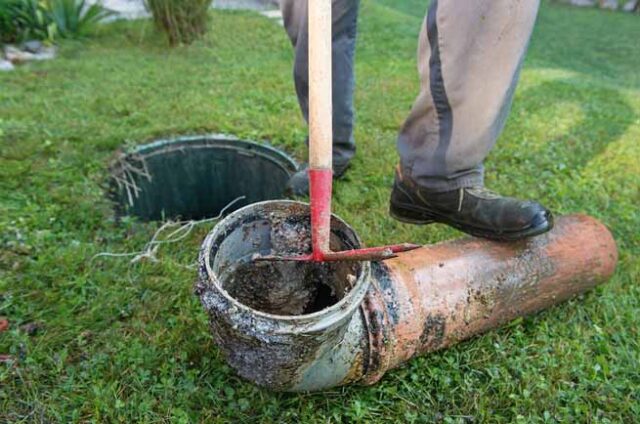 a person using a shovel to break a drain