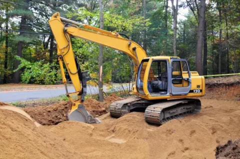 a yellow excavator digging a hole in dirt